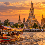 Bangkok ob sončnem zahodu – tempelj Wat Arun in čoln na reki Chao Phraya.
