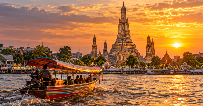 Bangkok ob sončnem zahodu – tempelj Wat Arun in čoln na reki Chao Phraya.